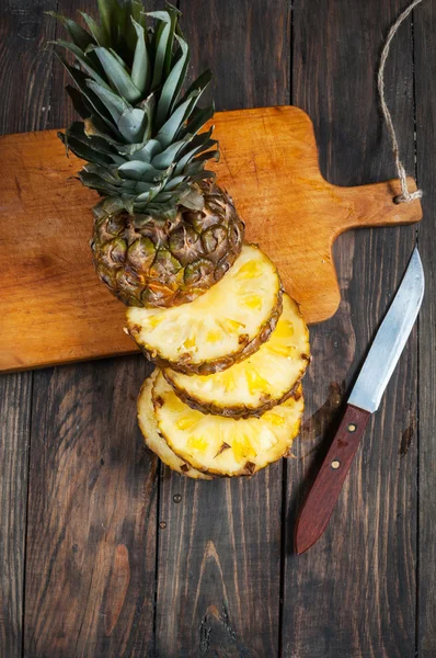 Färsk skivad ananas och kniv på ett bord av trä. — Stockfoto