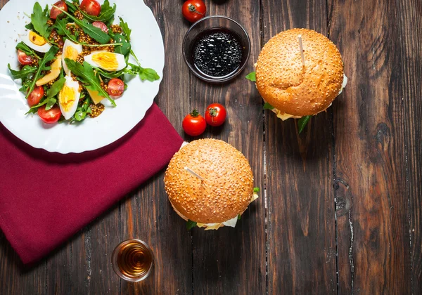 Bir salata roka ve koyu arka plan üzerinde alkol ile taze ev yapımı hamburger. Yukarıdan görüntüleyin. Üstten Görünüm.
