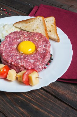 Biftek tartare ekmek ve ahşap arka plan üzerinde taze soğan ile.