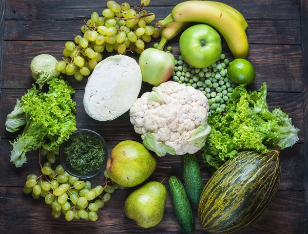 green vegetables and fruits on dark wooden background. Top view.