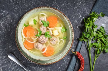 Köfte çorbası ve malzemeler taş masada. Üst görünüm.