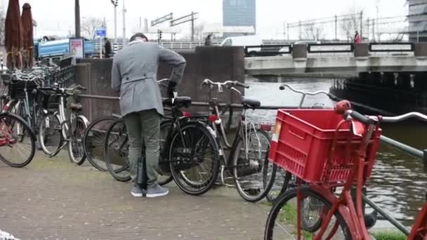 AMSTERDAM, Nizozemsko - 21. března 2019: muž před jízdou uklízí zaparkované kolo — Stock video