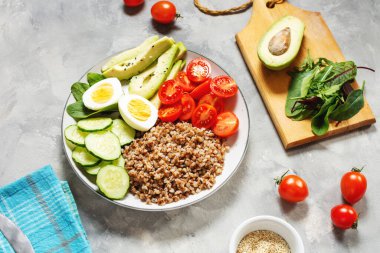 Avokado, yumurta, salatalık, domates ve karabuğdaylı vejetaryen yemek kasesi.