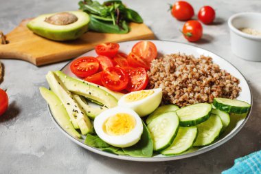 Avokado, yumurta, salatalık, domates ve karabuğdaylı vejetaryen yemek kasesi.