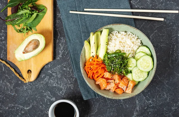 Salmon poke with avocado, seaweed, pickled carrots and cucumber on stone table. Top view — Stock Photo, Image