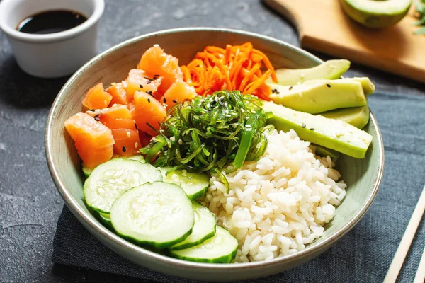 Salmon poke with avocado, seaweed, pickled carrots and cucumber on stone table. Royalty Free Stock Photos