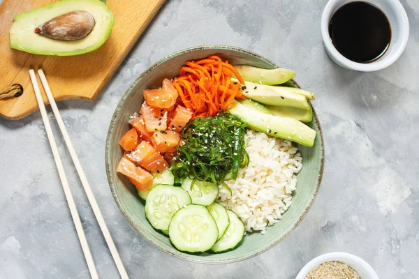 Salmon poke with avocado, seaweed, pickled carrots and cucumber on concrete table. Top — Stock Photo, Image