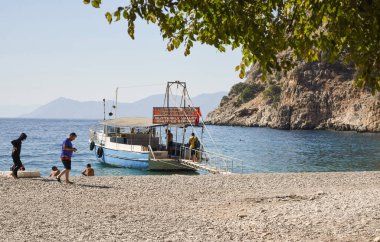 OLUDENIZ, TURKEY - 12 Eylül 2020: Turistler ünlü plajı ziyaret ederler. Kelebek Vadisi 'nde suda bir tekne.