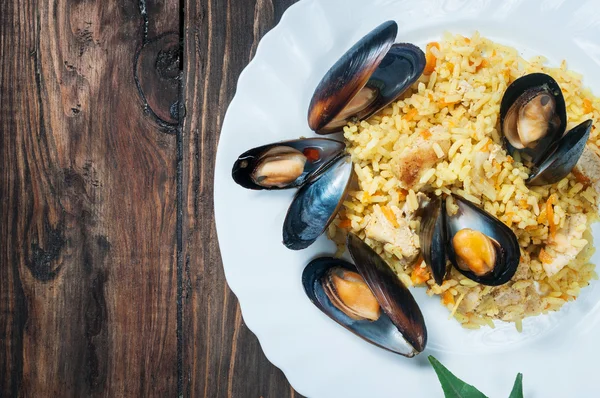 Ris med kött, grönsaker och musslor på en gammal tabell närbild — Stockfoto