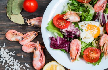 Sağlıklı karides ve ahşap bir masa üzerinde domatesli Roka Salatası