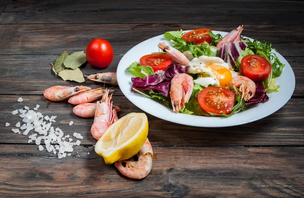 Gezonde garnalen en rucola salade met tomaten op een houten tafel — Stockfoto