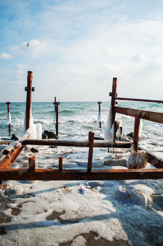 Frozen winter sea with wooden pole. Vertical