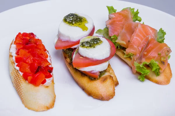Conjunto bruschetta italiano (mini sanduíche) com tomate, mussarela e salmão — Fotografia de Stock