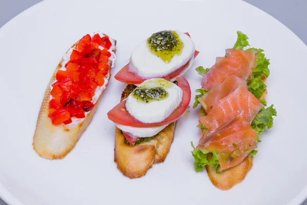 Conjunto bruschetta italiano (mini sanduíche) com tomate, mussarela e salmão — Fotografia de Stock