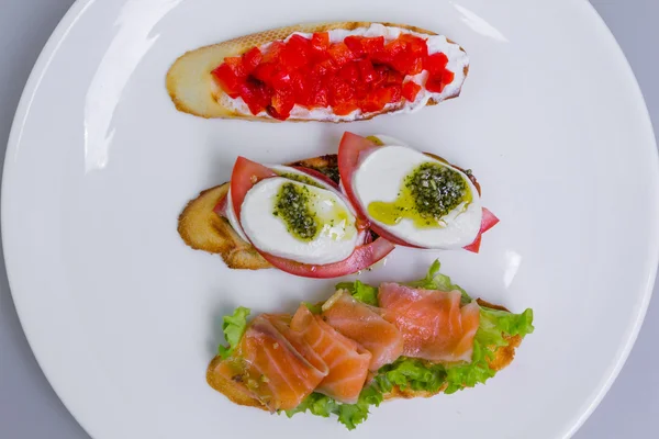 Conjunto bruschetta italiano (mini sanduíche) com tomate, mussarela e salmão — Fotografia de Stock