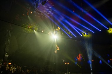 Sirk akrobatları sahne ışıkları altında motorsikletle yüksek telli dublörlük yapıyorlar. Toronto, Kanada - 19 Ekim 2025.