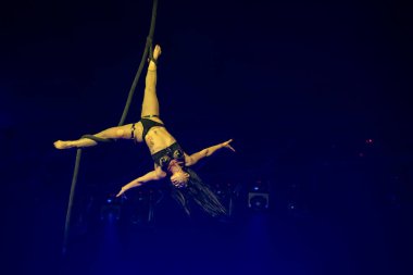 Sirk akrobatları mavi sahne ışıkları altında havadan ipek gösterisi yapıyorlar. Toronto, Kanada - 19 Ekim 2025.