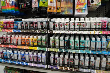 Mağaza rafındaki renklere göre düzenlenmiş çeşitli akrilik boya şişelerinin görüntüsü. Toronto, Kanada - 26 Kasım 2025.