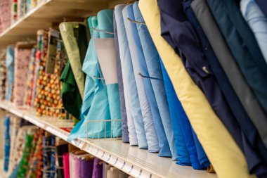 Bir mağaza rafında düzenlenmiş renkli kumaş cıvataları kapat.