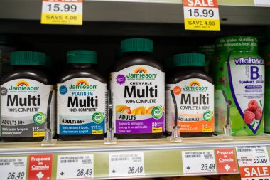 Erzak rafındaki yetişkinler için multivitamin şişelerini kapatın. Toronto, Kanada - 3 Aralık 2025.