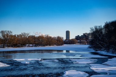 Kış manzarasında kısmen donmuş nehir manzarası.