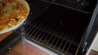 Donmuş peynirli pizzayı fırına koyup pişirmeye yakın.