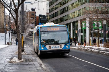 Şehir otobüsü STM kışın Montreal caddesinde yolda. Montreal, Kanada - 18 Aralık 2025.