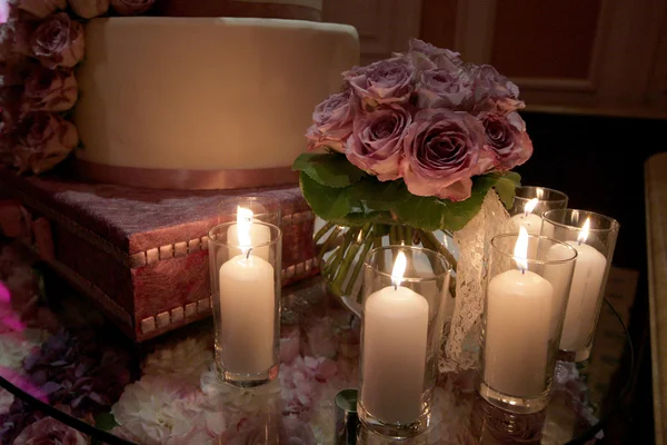 Düğün pastası, mumlar ve masanın üzerine gül