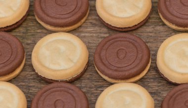 Tek bir bisküvinin içinde üç çeşit, iki taraflı ve ortasında da lezzetli bir krema. Ahşap arkaplan ve kapat