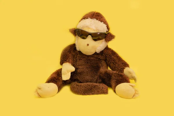 Plüsch-Affe mit Sonnenbrille auf gelbem Hintergrund — Stockfoto