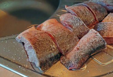 Pişirme işlemi sırasında mutfakta çiğ balık dilimleri var..