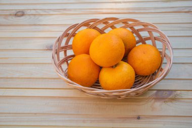 Ahşap bir arka planda sepetteki portakallar..