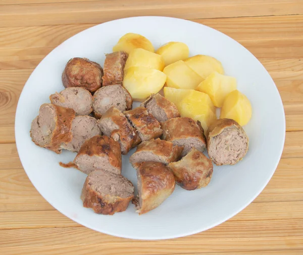 Prato de deliciosas fatias de salsicha com batatas em um fundo de madeira — Fotografia de Stock