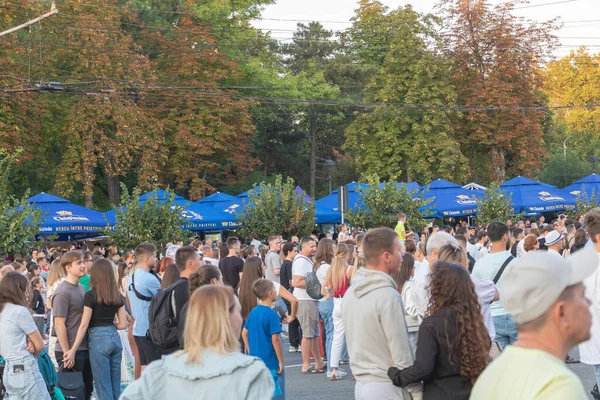 Bir halk yaz festivali sırasında açık havada mavi şemsiyelerin altında toplanan kalabalık, arka planda ağaçlar - Chisinau, Moldova - 27 Ağustos 2025