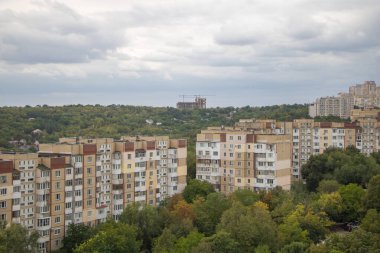 Ormanlık tepeleri ve bulutlu gökyüzünün altındaki uzak inşaatı olan Sovyet tarzı apartmanlar..