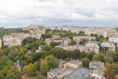 Doğu Avrupa şehrinde bulutlu gökyüzü altında konut binalarının ve yeşil kentsel manzaranın hava panoramik manzarası.