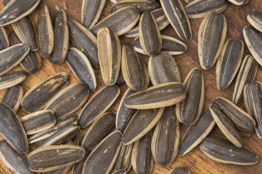 Ahşap yüzeyde kabukları, doğal atıştırmalıkları ve besin maddeleri olan siyah ayçiçeği tohumlarının yakın çekim makrosu..