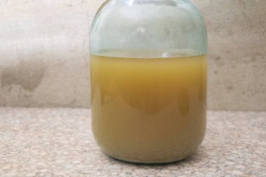 Mutfak yüzeyinde cam kavanozda ev yapımı filtresiz beyaz şarap. Doğal çökeltisi olan geleneksel kırsal içecek..