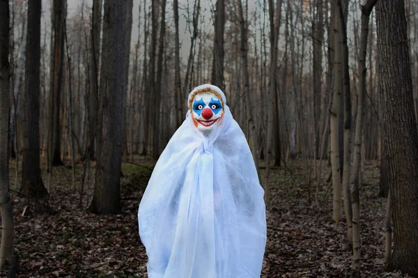 Böser Clown in einem dunklen Wald in einem weißen Schleier — Stockfoto