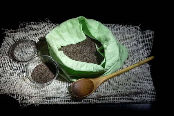 Cabbage seeds in a bag and a wooden spoon. Collection, storage and preparation of seeds for planting. On a dark background.