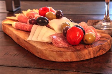 Prosciutto, mozzarella peyniri, Ceneviz salamı, Fontina peyniri ve zanaatkar krakerlerinin arkasında mumlar olan köy tahtası..