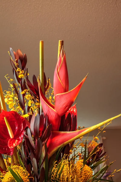 Tropical bouquet of flowers including Heliconia bihai, yellow oncidium orchids, yellow pincushion protea, and red anthuriums.