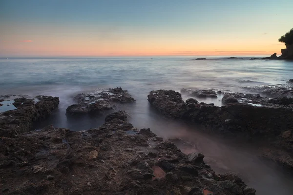 Longa exposição do pôr do sol sobre as rochas — Fotografia de Stock