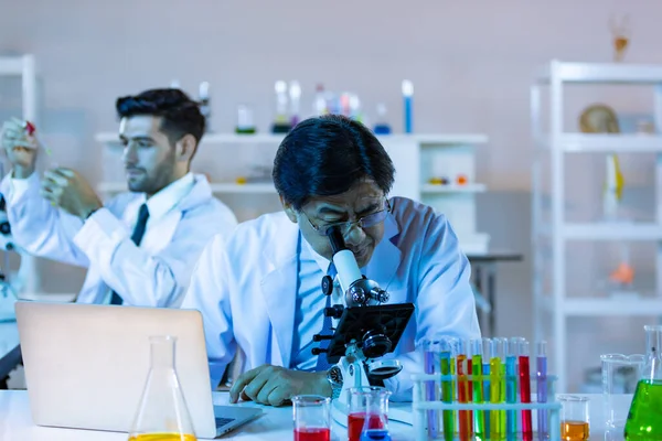 为研究亚洲科学家的化学数据 微生物学家生物技术研究人员或医务工作者小组在实验室内进行显微镜检查 — 图库照片
