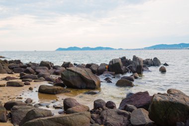 Sahil taşlar ve yaz aylarında bulutlu gökyüzü üzerinde dalga deniz