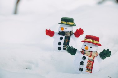 Park kar yığını arasında iki kar adam stand. Sunshine warmi olduğunu