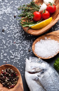 taze çiğ dorado balık baharat ve otlar üzerinde siyah arka plan, üstten görünüm