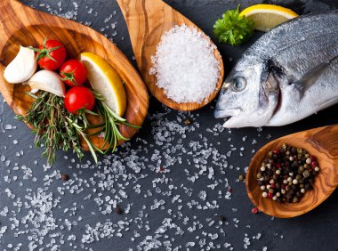 taze çiğ dorado balık baharat ve otlar üzerinde siyah arka plan, üstten görünüm