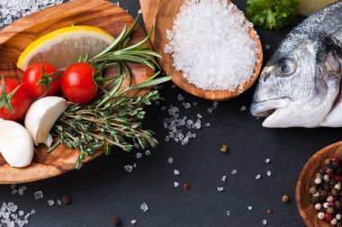 taze çiğ dorado balık baharat ve otlar üzerinde siyah arka plan, üstten görünüm