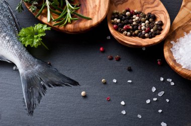 taze çiğ dorado balık baharat ve otlar üzerinde siyah arka plan, üstten görünüm